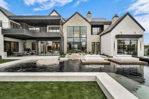 Rear view of property featuring a chimney, a patio, stucco siding, and stone siding