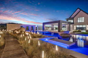 Back of property at dusk featuring an outdoor pool