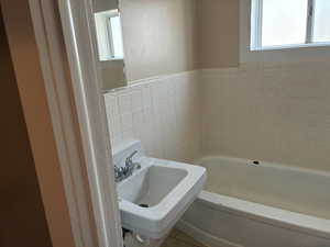 Full bath featuring a bath, tile walls, a wainscoted wall, and tile patterned flooring