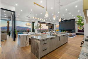 Kitchen featuring light stone countertops, open floor plan, light wood-type flooring, modern cabinets, and floor to ceiling windows