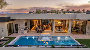 Rear view of property featuring an outdoor kitchen / dining area, a fire pit, a patio area, and an outdoor pool