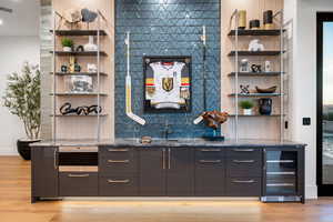 Indoor wet bar with open shelves, beverage cooler, and dark stone countertops
