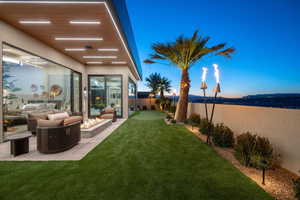 Yard at dusk with an outdoor living space with a fire pit, a water view, and a patio
