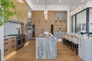 Kitchen featuring light stone counters, pendant lighting, modern cabinets, and range with two ovens