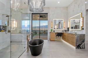 Bathroom featuring vanity, a soaking tub, a stall shower, light tile patterned flooring, and tile walls