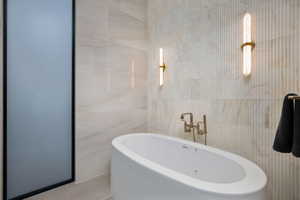 Bathroom featuring tile walls and a soaking tub