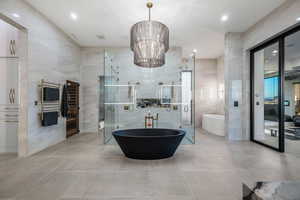 Full bathroom with a towel warmer, tile walls, a soaking tub, a shower stall, and tile patterned flooring