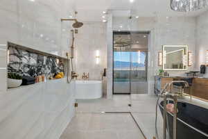 Full bath with a freestanding tub, tile walls, tile patterned floors, and a shower with shower door