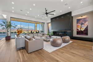 Living room featuring a multi sided fireplace, light wood-style floors, ceiling fan, and recessed lighting