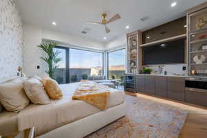 Bedroom with access to outside, a ceiling fan, beverage cooler, recessed lighting, and wet bar