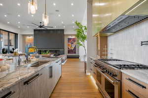 Kitchen featuring light stone counters, double oven range, open floor plan, light wood-type flooring, and modern cabinets