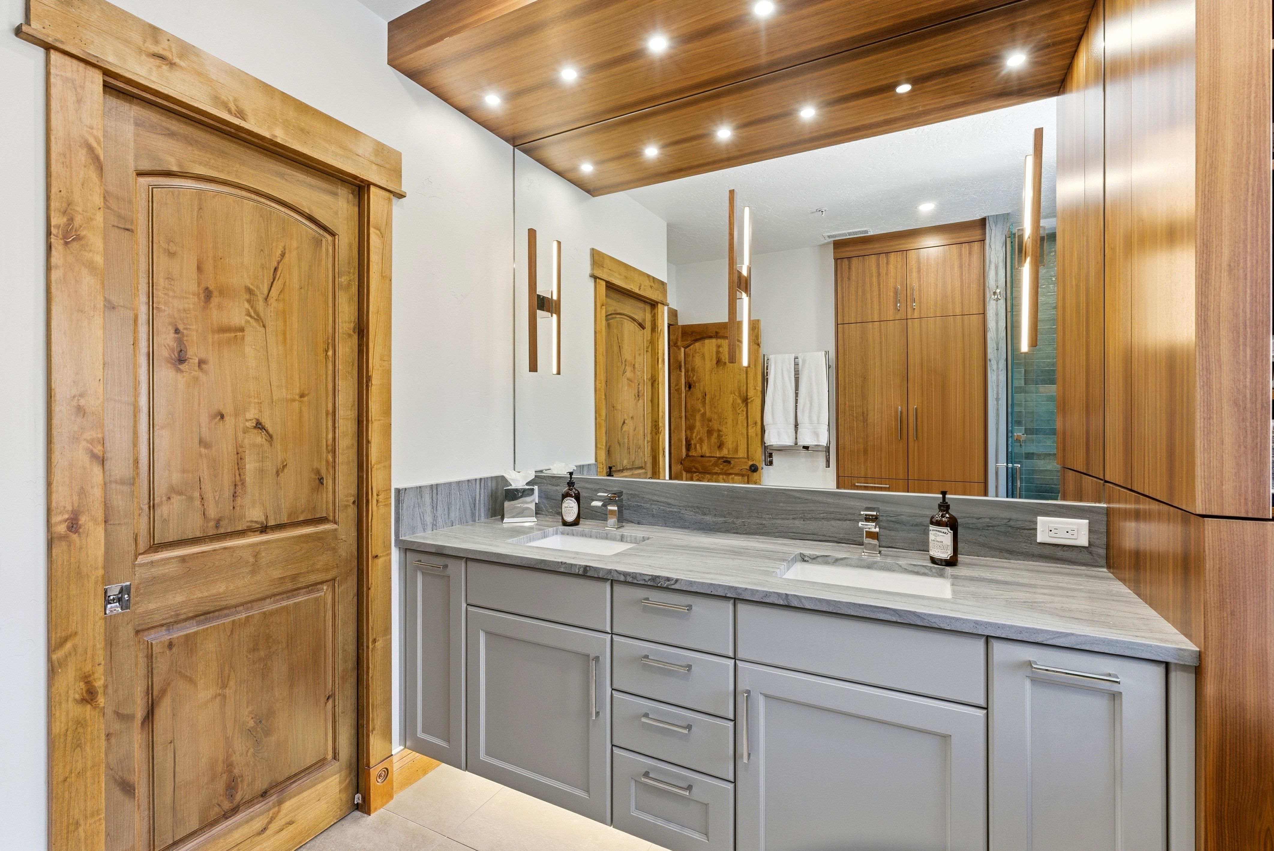 Dual vanity with light gray cabinetry, integrated sinks, and stone countertops