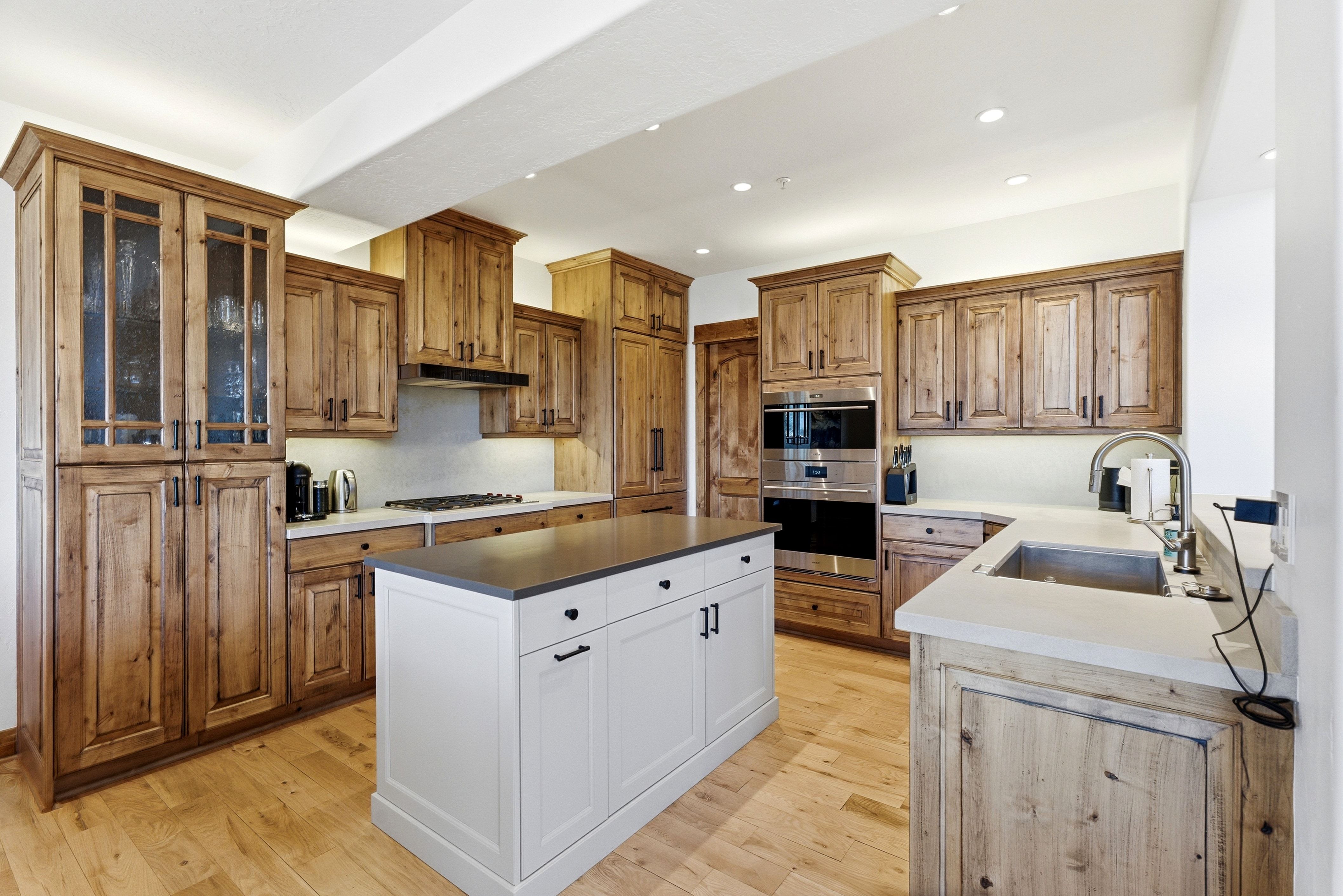 Kitchen featuring light wood-finish flooring, light wood cabinetry, and a white center island with a dark countertop