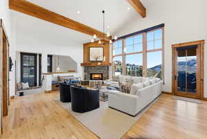Living area featuring a chandelier, light wood-style flooring, a stone fireplace, a mountain view, and lofted ceiling