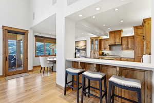 Kitchen featuring wood finish cabinetry, a kitchen breakfast bar, light wood finished floors, glass fronted cabinets, and recessed lighting
