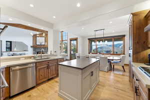 Dual tone kitchen featuring dual tone cabinets, stainless steel dishwasher, light wood-type flooring, hanging light fixtures, and a center island