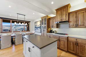 Dual tone kitchen with hanging light fixtures, a center island, a mountain view, light wood finished floors, and dual tone cabinetry