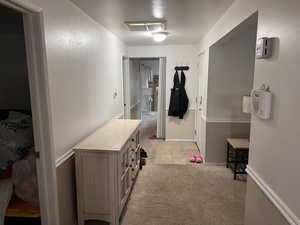 Corridor with light colored carpet and baseboards