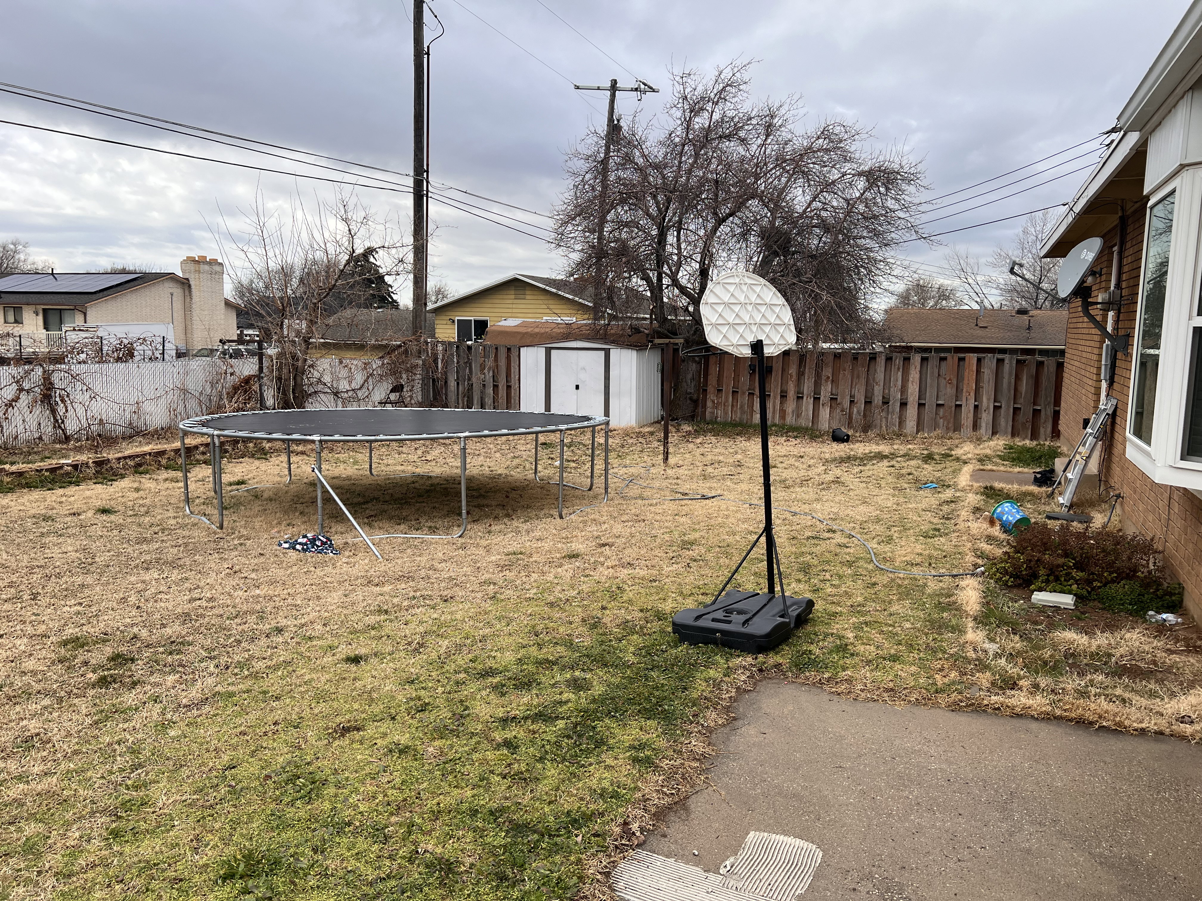 Fenced backyard featuring a storage unit and a trampoline