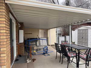 View of patio featuring outdoor dining area and a shed