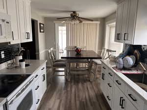 Kitchen with tasteful backsplash, white cabinetry, white appliances, and ceiling fan