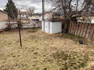 Fenced backyard featuring a storage shed and a residential view