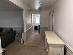 Hallway featuring light carpet and baseboards