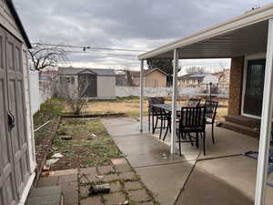 Fenced backyard with a patio, outdoor dining area, and a shed