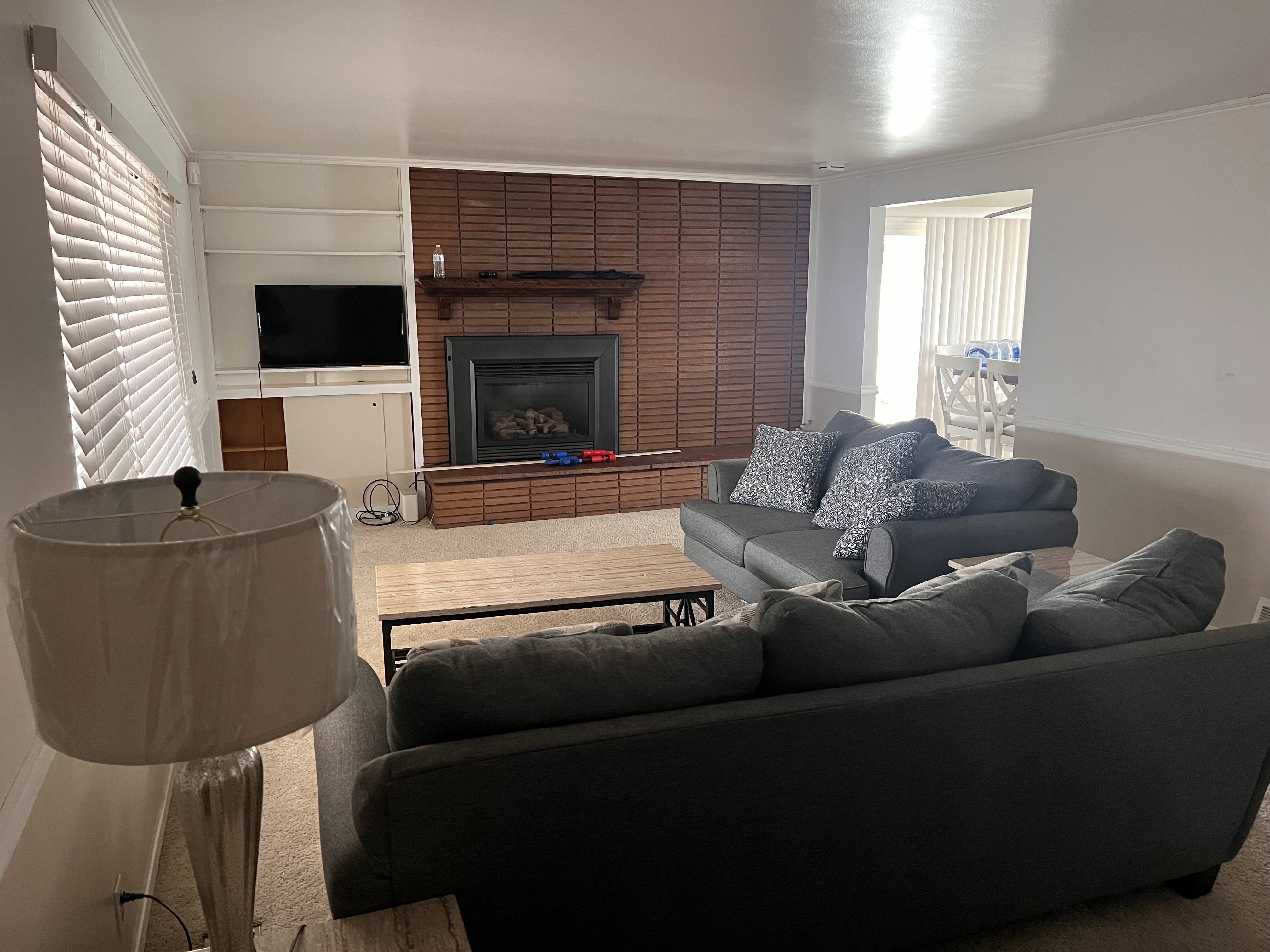 Carpeted living area with crown molding and a large fireplace