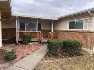 Property entrance featuring brick siding and a wooden deck
