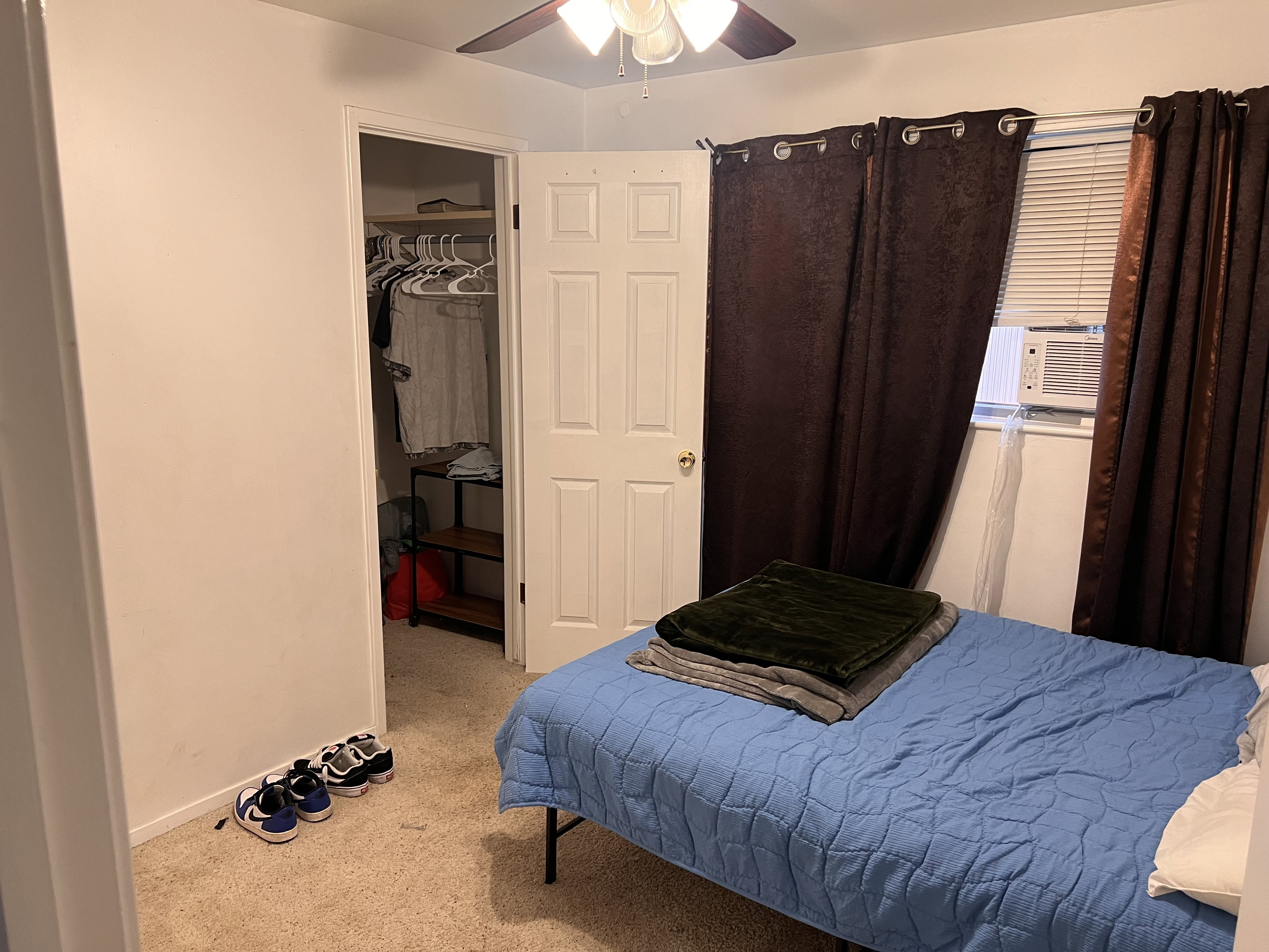 Bedroom with light carpet, a spacious closet, a ceiling fan, and cooling unit