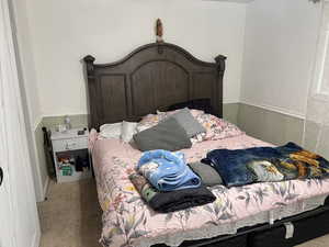 Bedroom featuring wainscoting, light colored carpet, and wooden walls