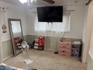 Playroom with wainscoting, a ceiling fan, light colored carpet, and wooden walls