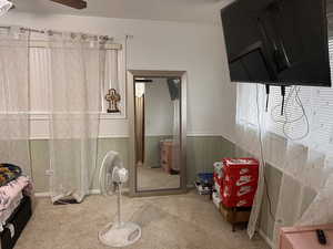 Bedroom with wainscoting, carpet flooring, and a ceiling fan