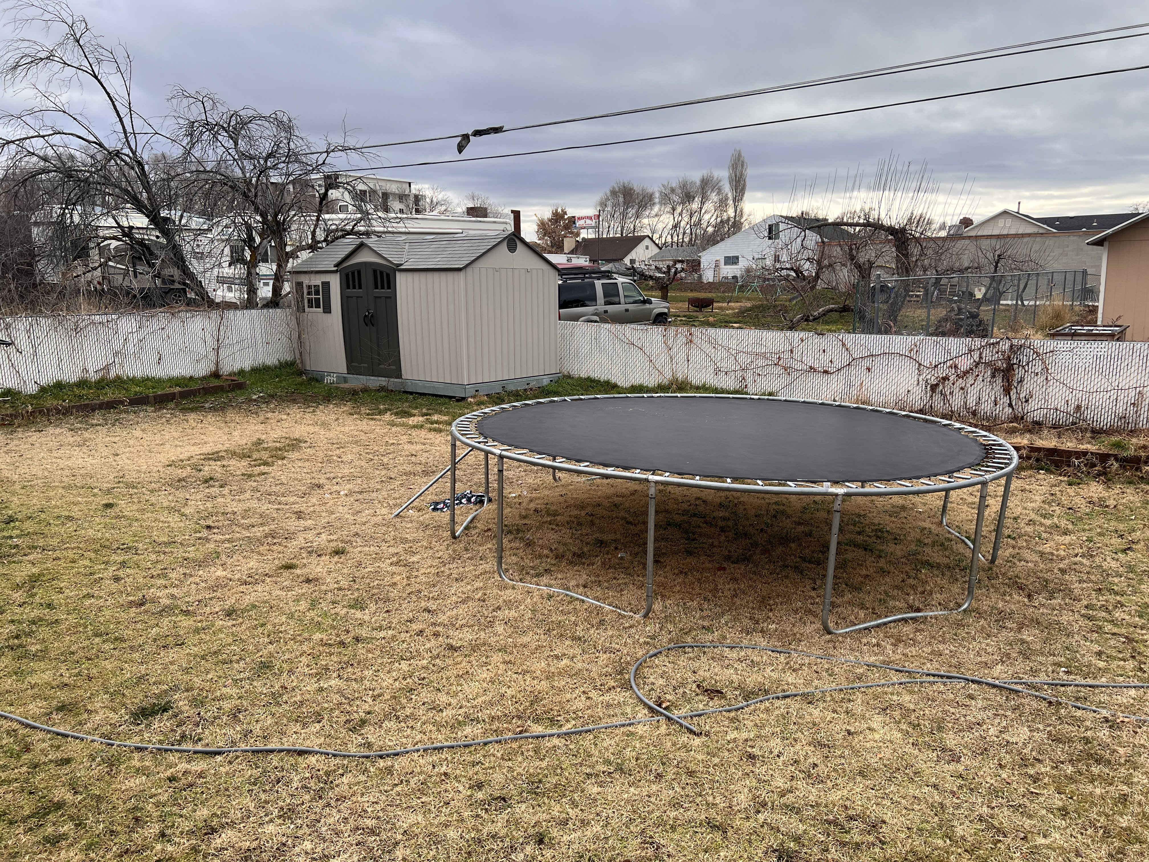 Fenced backyard featuring a residential view, a trampoline, and a shed