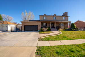 Traditional home featuring covered porch, driveway, an attached garage, brick siding, and a chimney