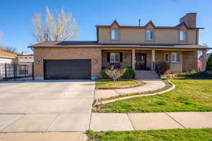 View of front of property with a front lawn, concrete driveway, an attached garage, covered porch, and brick siding