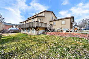Back of house with stucco siding, a deck, and a patio