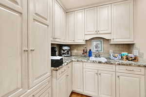 Kitchen featuring light stone countertops, decorative backsplash, and light wood finished floors