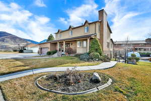 Traditional-style house featuring a porch, a chimney, an attached garage, a mountain view, and concrete driveway