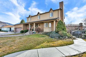 Traditional-style home with a garage, a chimney, stucco siding, and brick siding