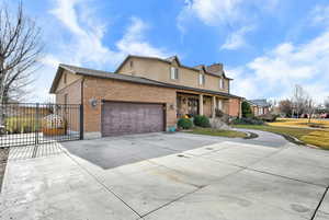 Traditional-style home with covered porch, driveway, brick siding, and an attached garage
