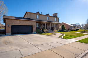 Traditional-style house featuring covered porch, an attached garage, concrete driveway, brick siding, and a front lawn