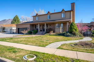 Traditional-style home with a porch, a garage, brick siding, driveway, and a chimney
