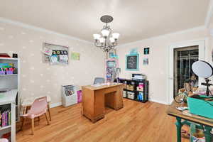 Home office featuring hanging lights, light wood-style floors, and ornamental molding