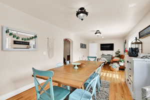 Dining room with arched walkways and light wood-style flooring