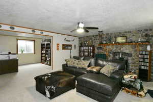 Living area with a textured ceiling, carpet, a ceiling fan, and ornamental molding