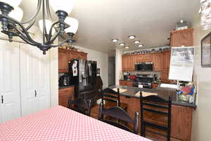 Kitchen with a chandelier, a peninsula, stainless steel appliances, wood finish cabinetry, and a kitchen breakfast bar