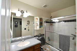Bathroom featuring vanity and enclosed tub / shower combo