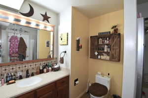 Full bath featuring vanity and decorative backsplash